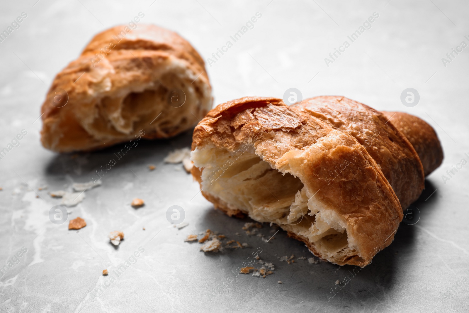 Photo of Tasty fresh croissant on light grey marble table, closeup