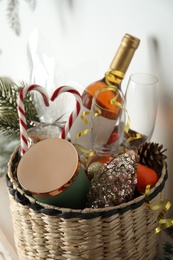 Photo of Wicker basket with gift set and Christmas decor near white wall