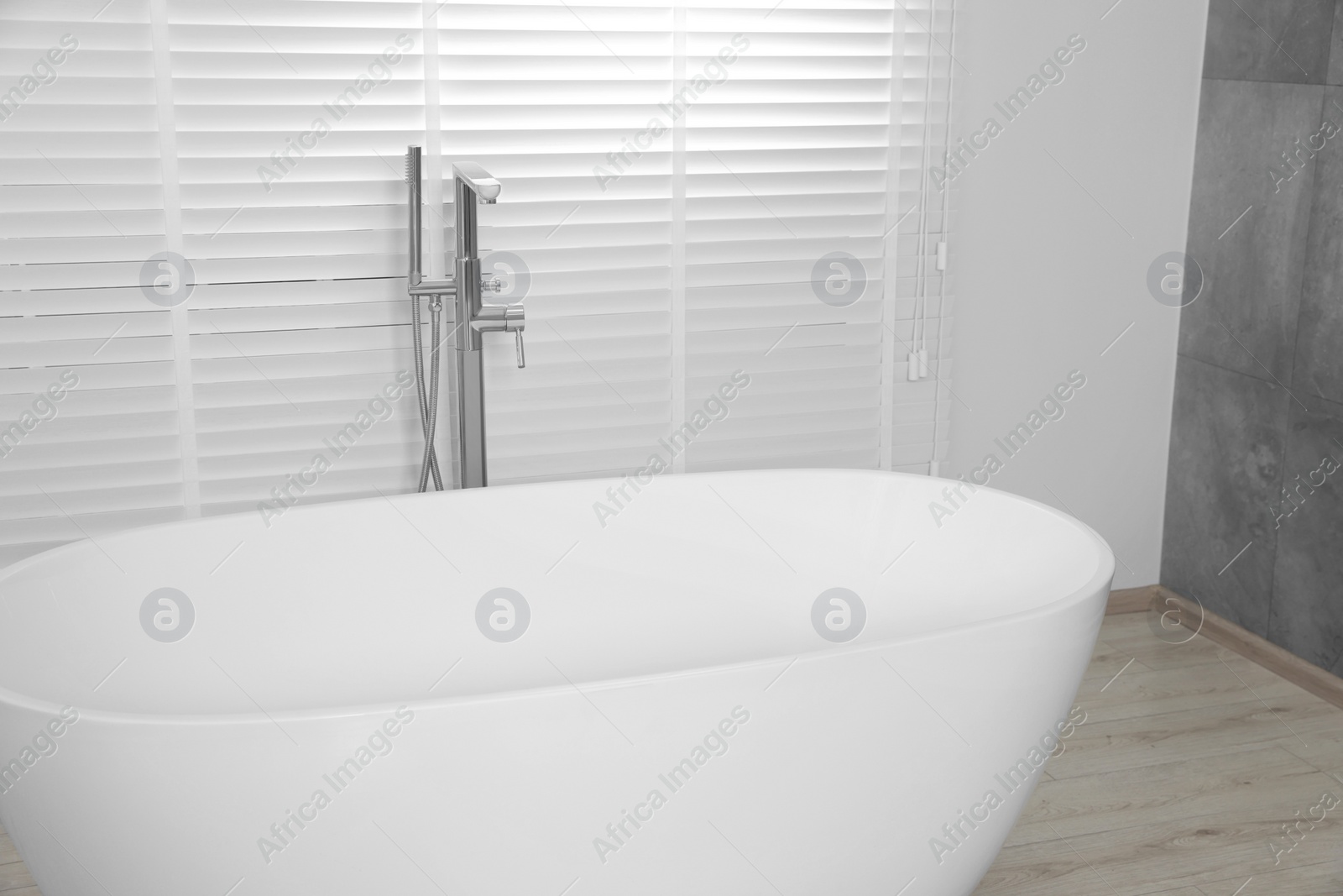 Photo of Stylish ceramic tub near window with blinds indoors, closeup