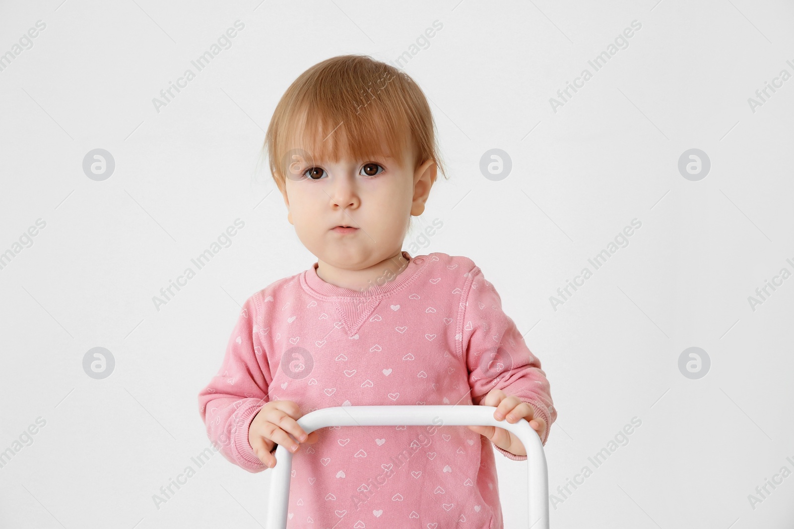 Photo of Cute baby playing with toy walker on light background