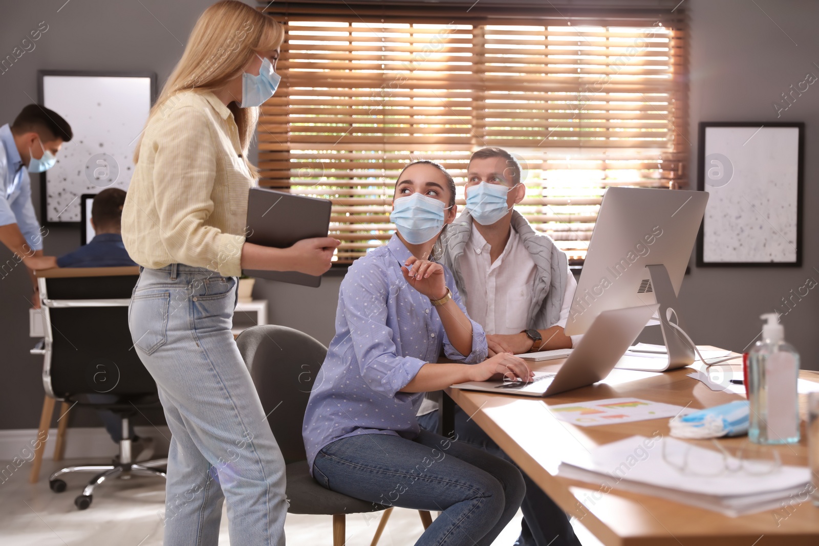 Photo of Coworkers with masks in office. Protective measure during COVID-19 pandemic