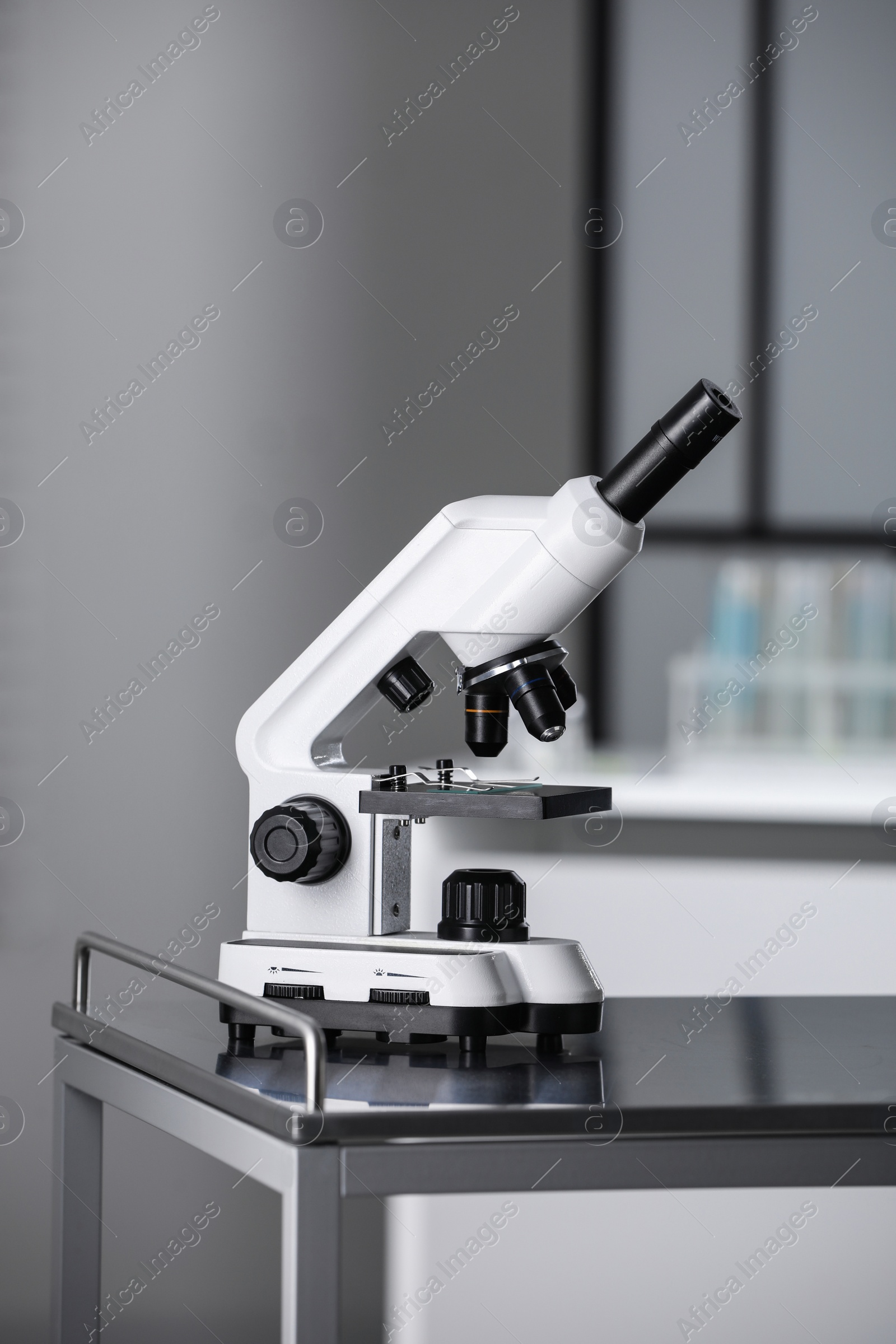 Photo of Modern medical microscope on metal table in laboratory