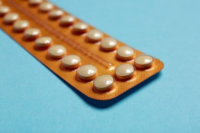 Photo of Birth control pills on light blue background, closeup