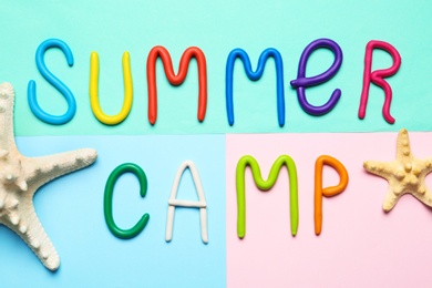 Photo of Text SUMMER CAMP made of modelling clay and starfishes on color background, flat lay