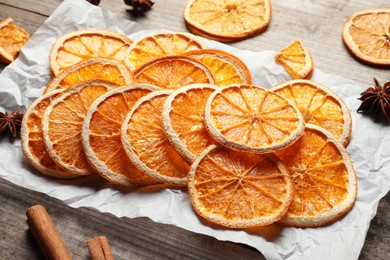 Many dry orange slices and spices on wooden table, closeup