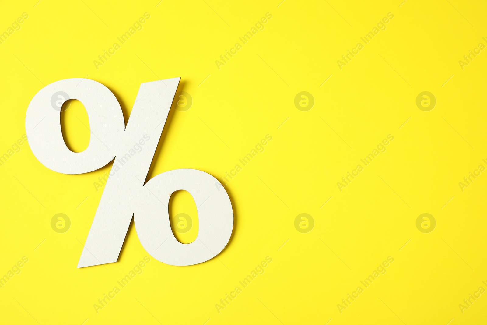 Photo of White percent sign on yellow background, top view. Space for text