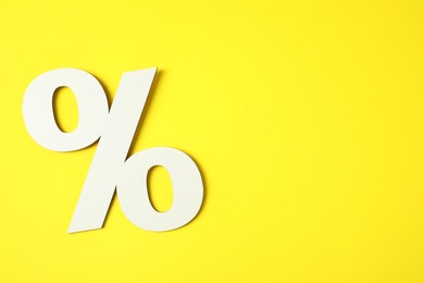 Photo of White percent sign on yellow background, top view. Space for text