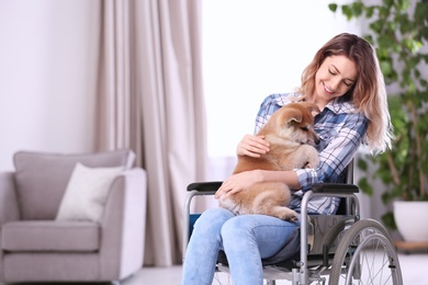 Photo of Young woman in wheelchair with puppy at home