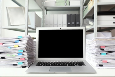 Photo of Laptop and documents on desk in office. Space for text