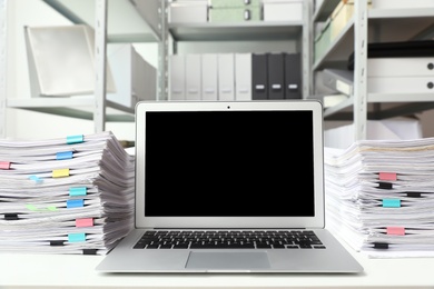 Laptop and documents on desk in office. Space for text