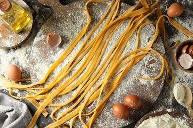Photo of Homemade pasta, flour, eggs and oil on table, flat lay