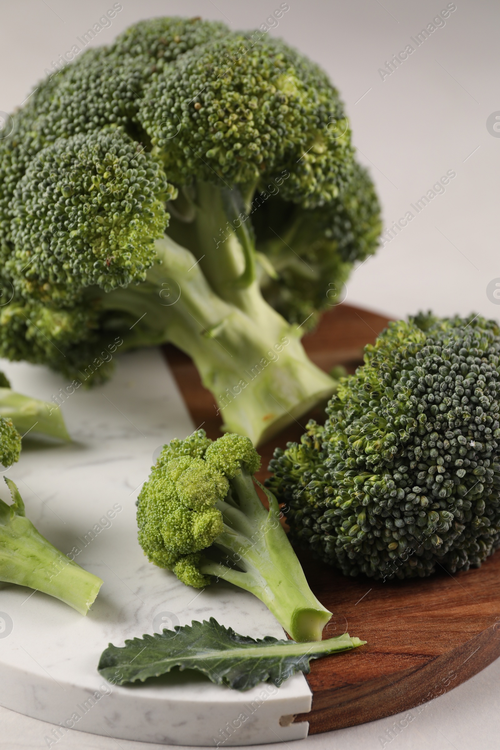 Photo of Tray with fresh raw broccoli on white table, closeup