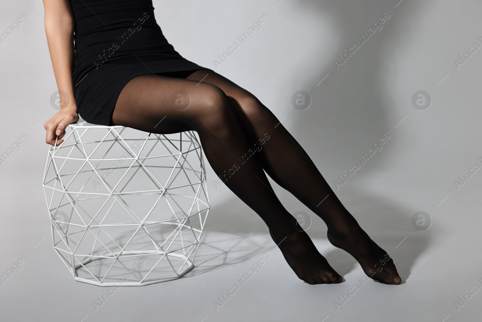 Photo of Woman with beautiful long legs wearing black tights on light background, closeup