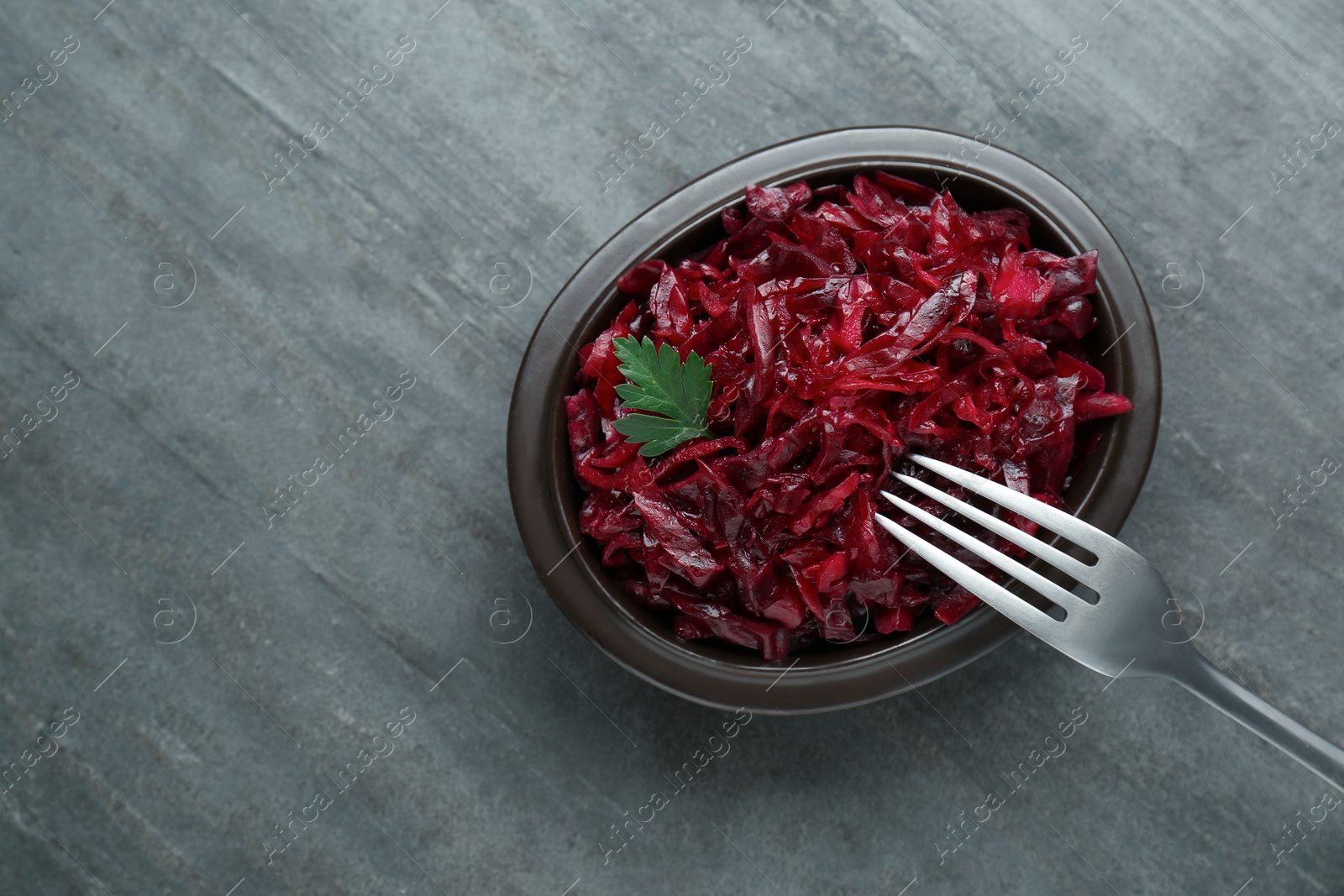 Photo of Tasty red cabbage sauerkraut with parsley on grey table, top view. Space for text