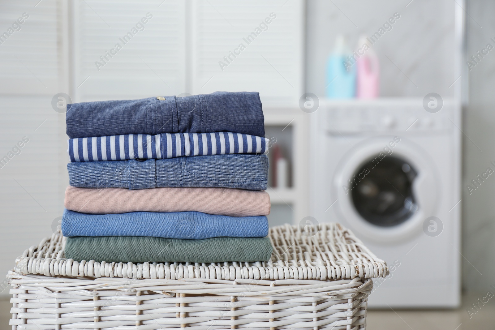Photo of Stack of fresh laundry on basket in bathroom