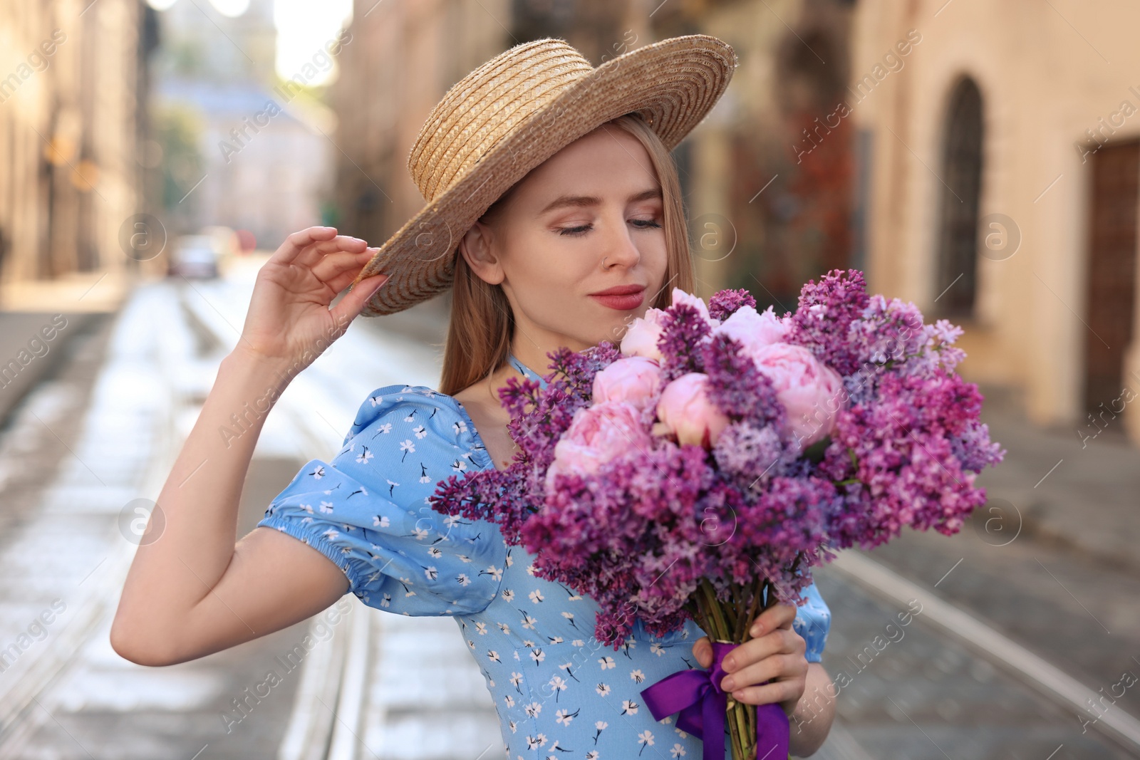 Photo of Beautiful woman with bouquet of spring flowers on city street