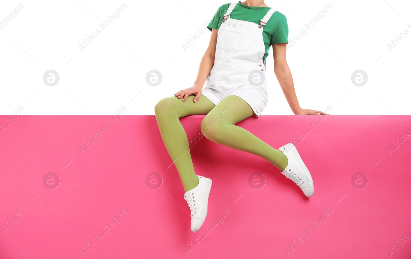 Photo of Woman wearing green tights and stylish shoes sitting on color background, closeup