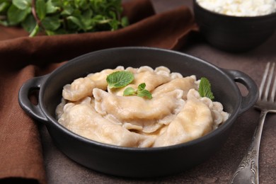 Photo of Delicious dumplings (varenyky) with cottage cheese and mint served on brown table