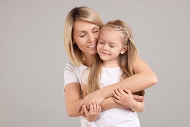 Photo of Happy mother and daughter hugging on grey background