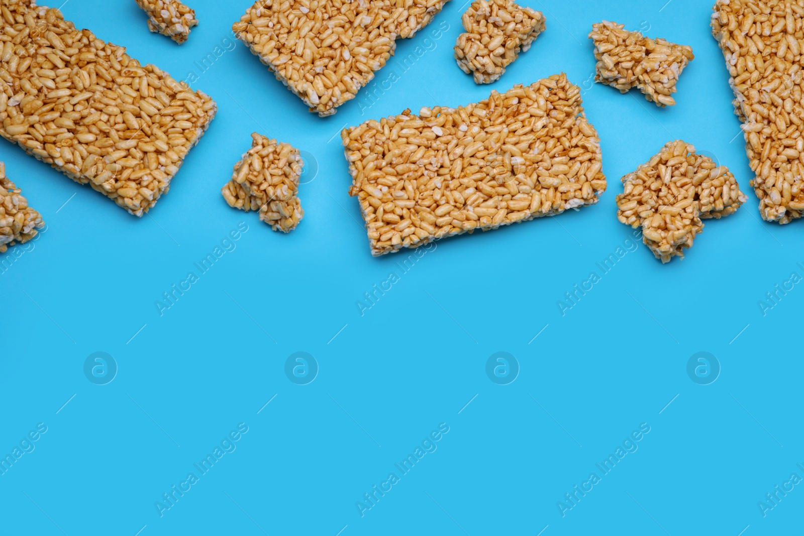 Photo of Puffed rice bars (kozinaki) on light blue background, flat lay. Space for text