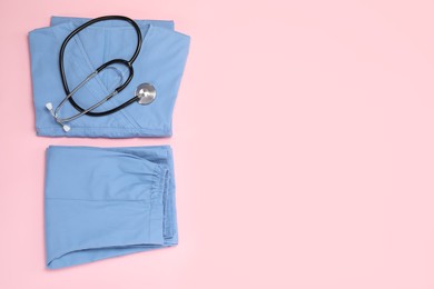 Medical uniform and stethoscope on pink background, flat lay. Space for text