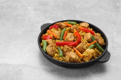 Photo of Serving pan of delicious rice with chicken and vegetables on light grey table