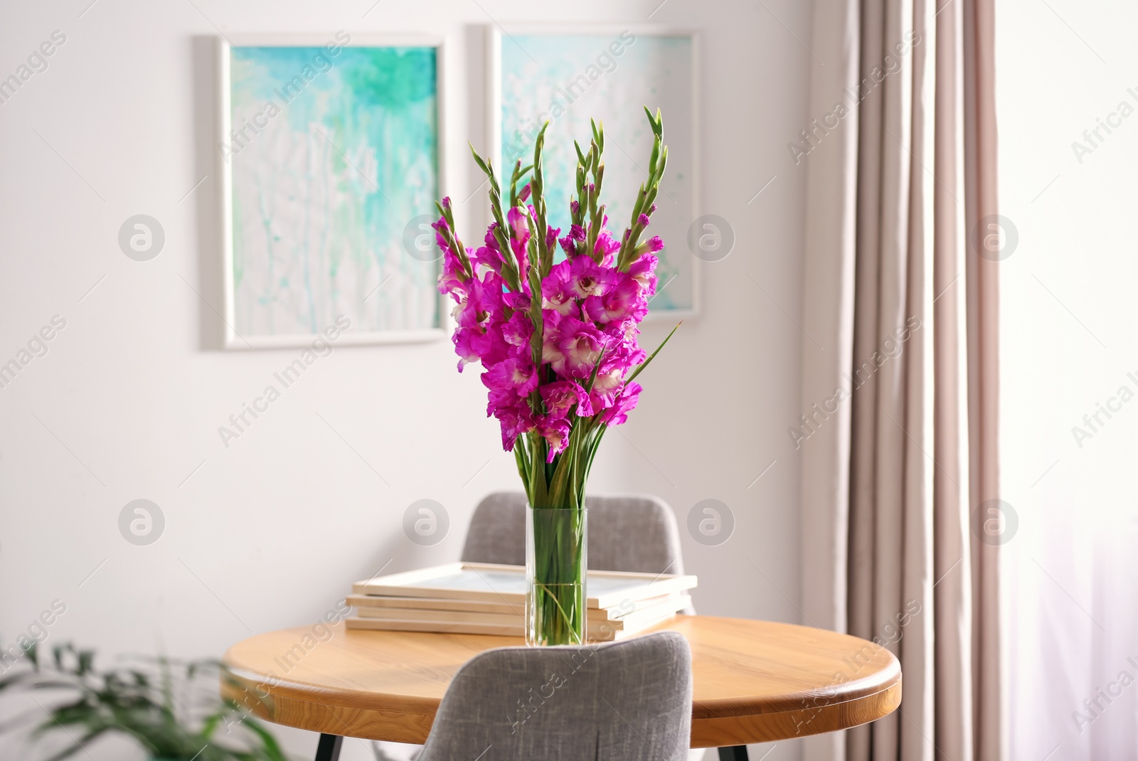 Photo of Vase with beautiful pink gladiolus flowers on wooden table in room, space for text