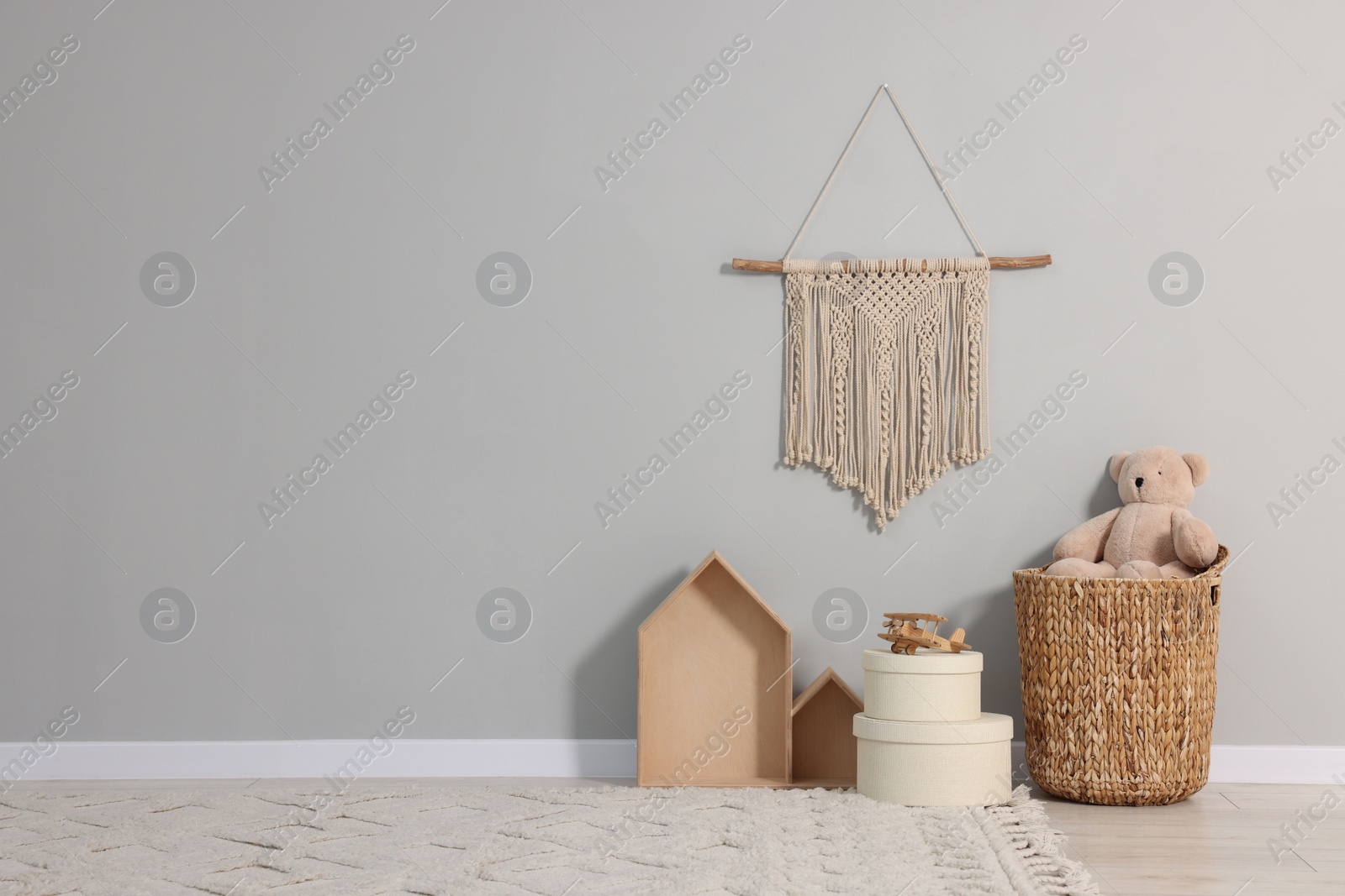 Photo of Beautiful children's room with grey wall, decor elements and toys, space for text. Interior design