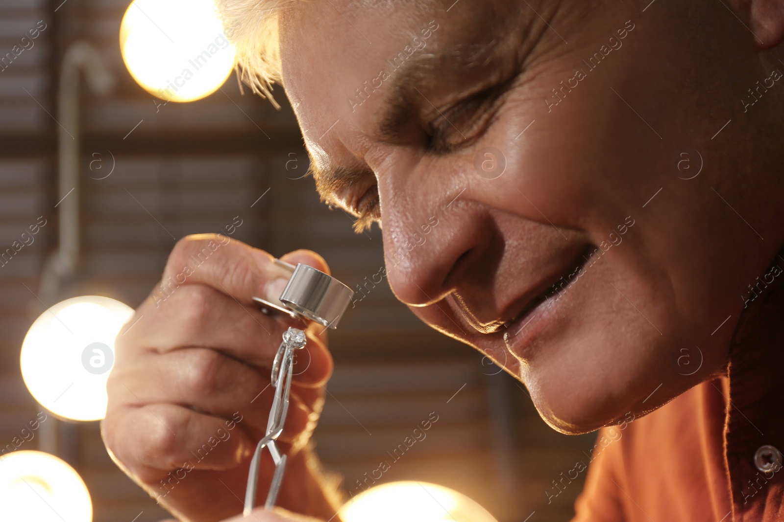 Photo of Professional jeweler evaluating beautiful ring in workshop, closeup