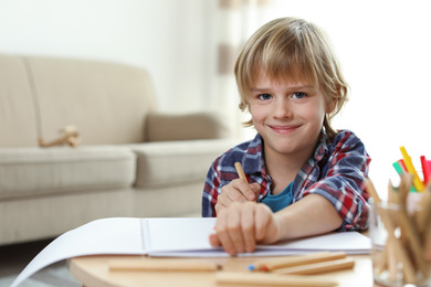 Photo of Little boy drawing at table indoors. Creative hobby