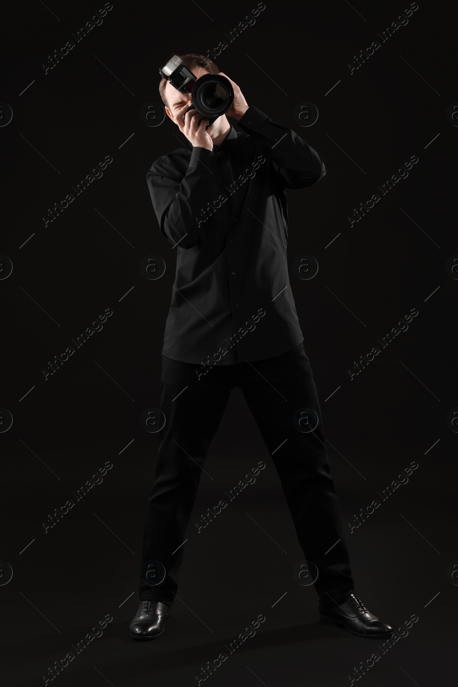 Photo of Professional photographer taking picture on black background