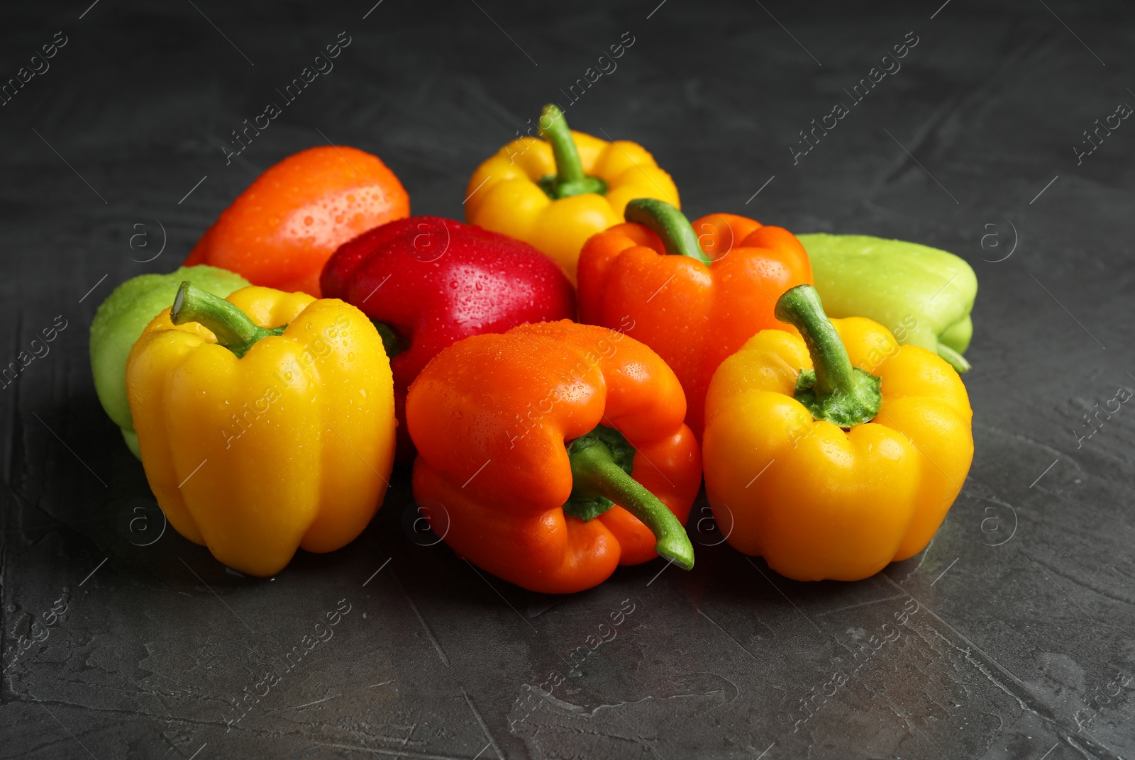 Photo of Wet ripe bell peppers on grey table