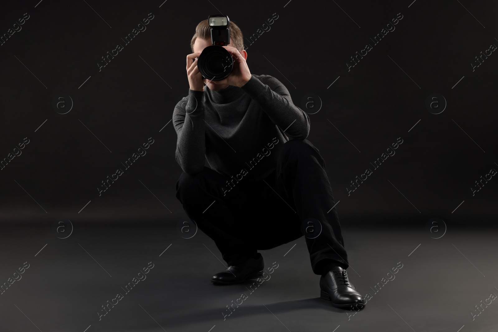 Photo of Professional photographer taking picture on black background