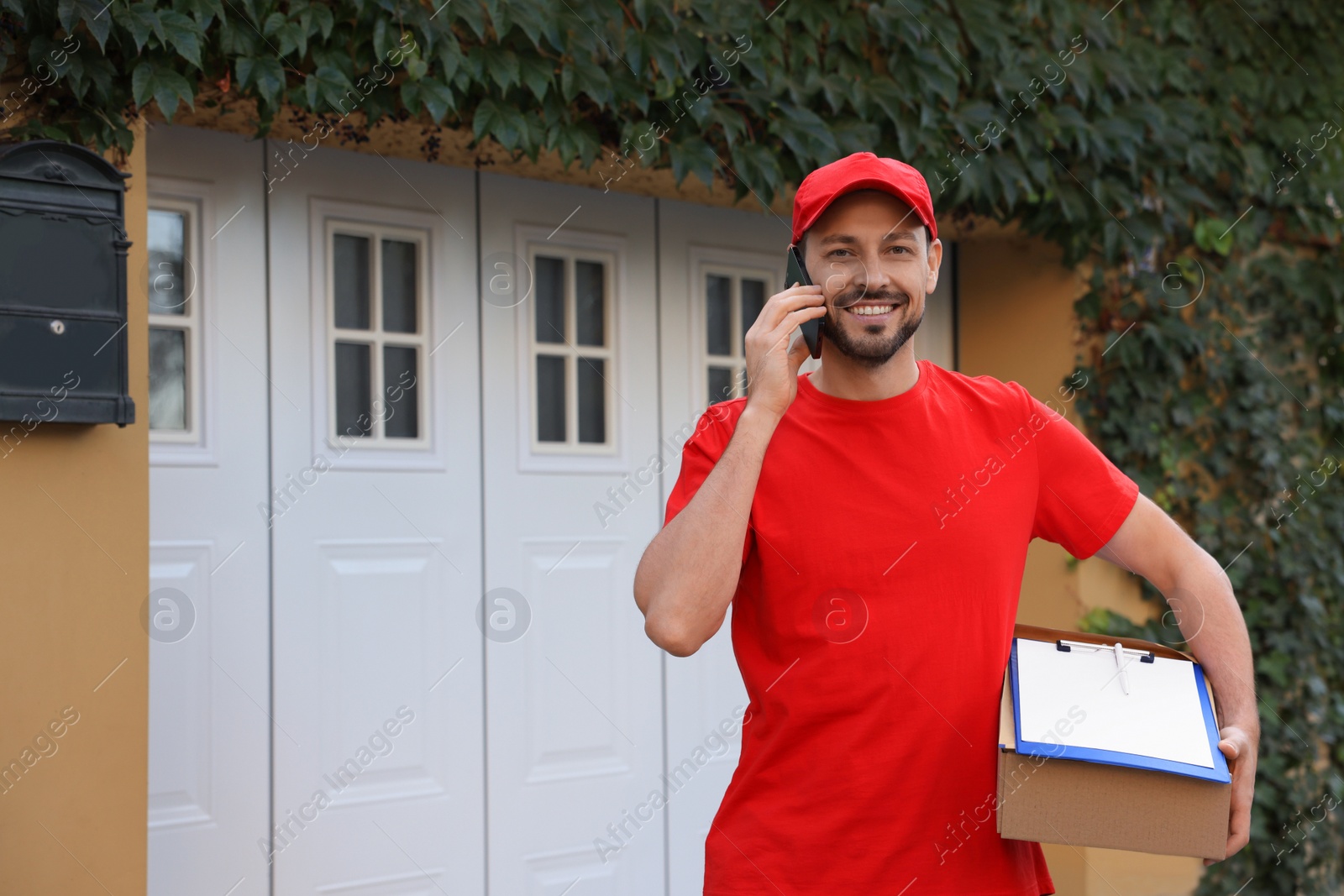 Photo of Courier with parcel talking on smartphone outdoors, space for text. Order delivery