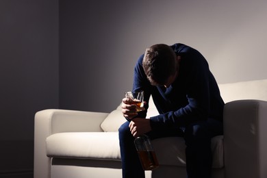 Photo of Addicted drunk man with alcoholic drink on sofa indoors. Space for text