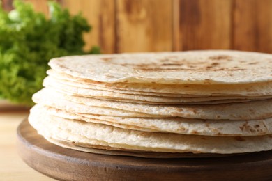 Photo of Many tasty homemade tortillas on wooden table, closeup