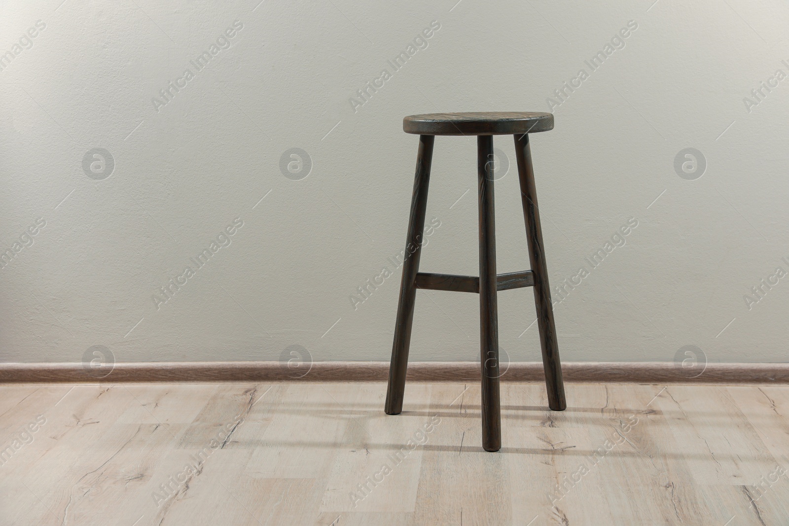 Photo of Stylish wooden stool near light wall indoors. Space for text