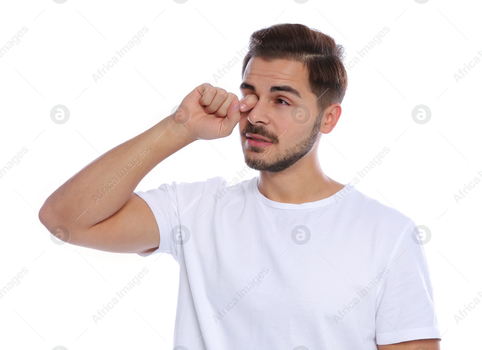 Photo of Young man rubbing eye on white background. Annoying itch