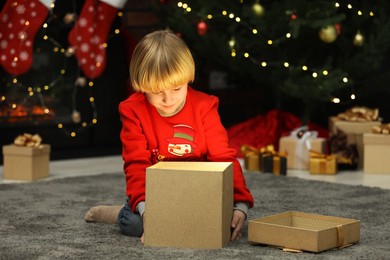 Photo of Little child with opening magic gift box at home. Christmas celebration