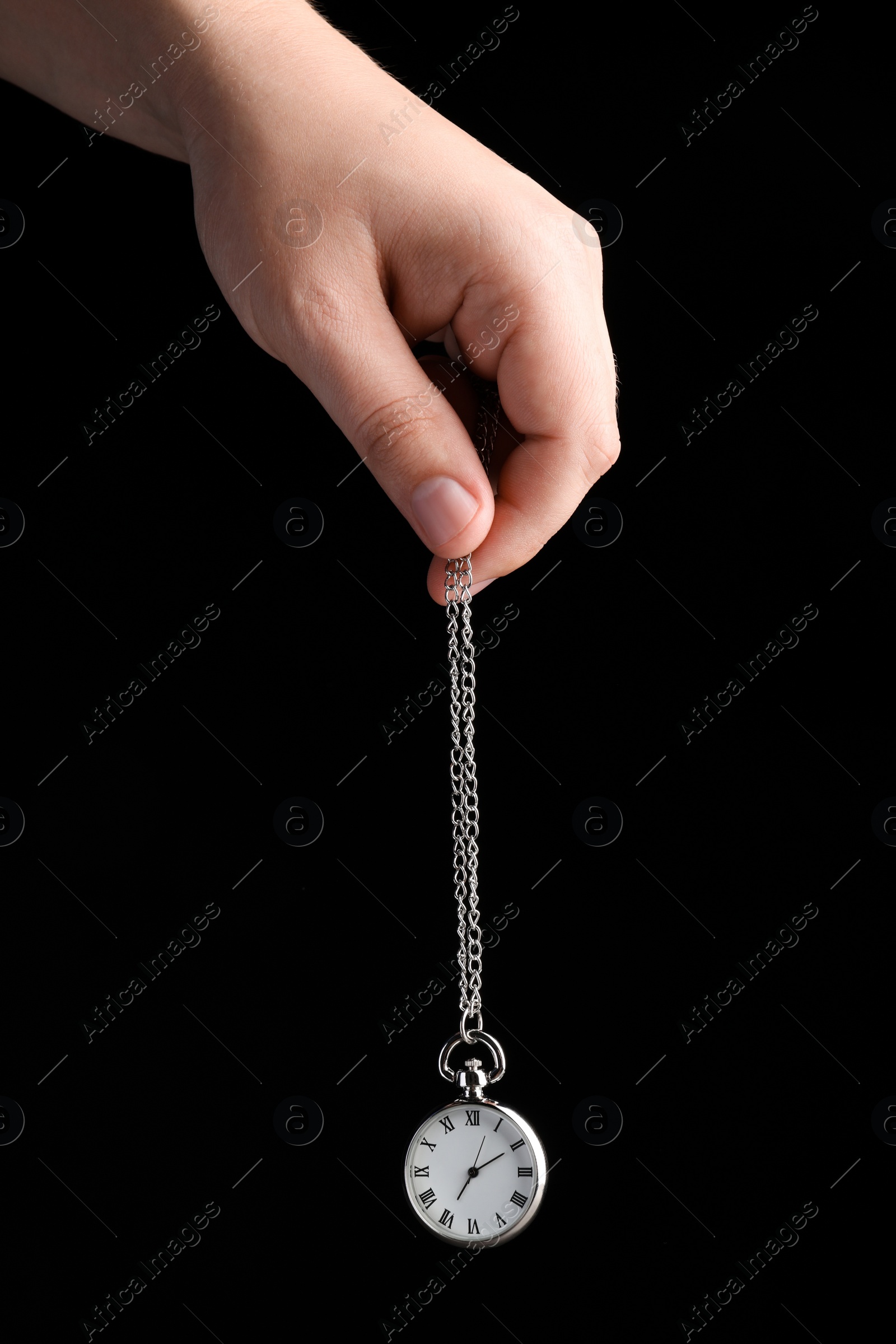 Photo of Psychotherapist with pendulum on black background, closeup. Hypnotherapy session