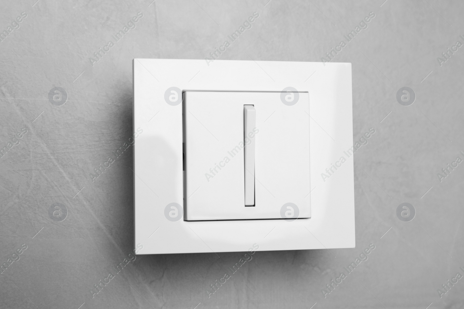 Photo of White light switch on grey background, closeup