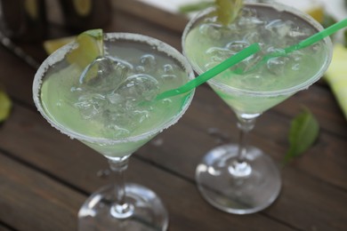 Photo of Delicious Margarita cocktail in glasses on wooden table, closeup