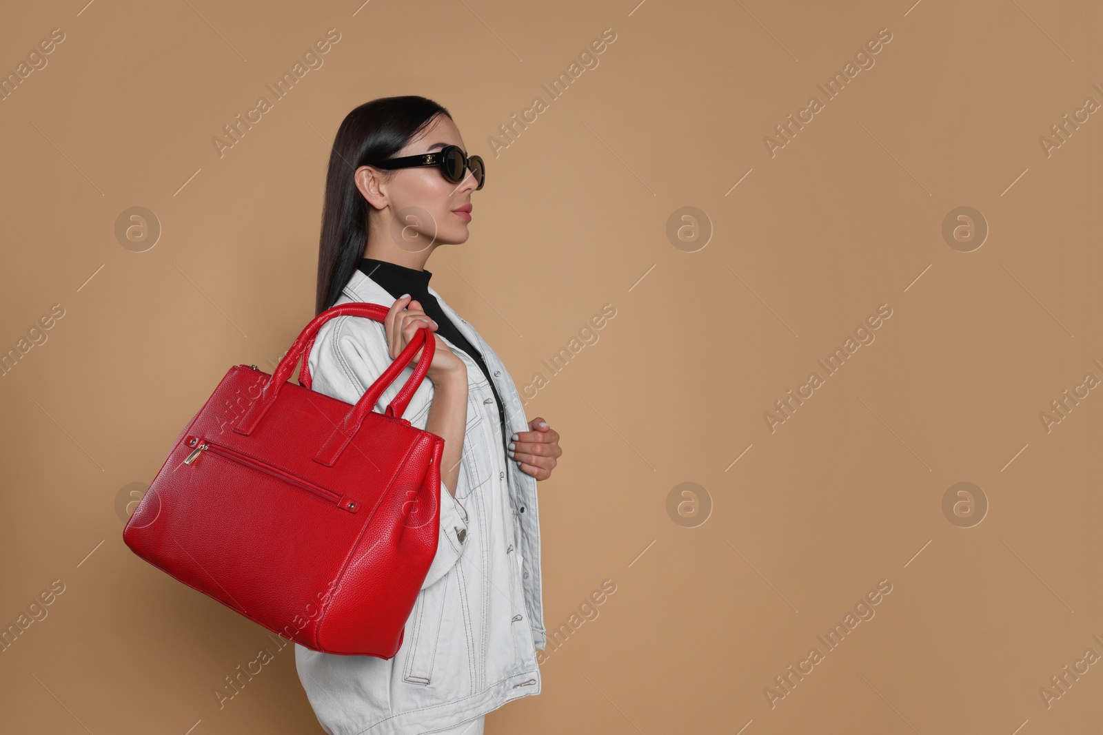 Photo of Young woman with stylish bag on beige background, space for text