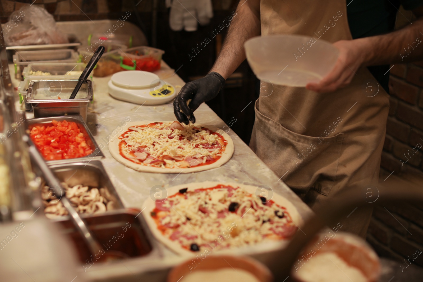 Photo of Man making pizzas at table, closeup view