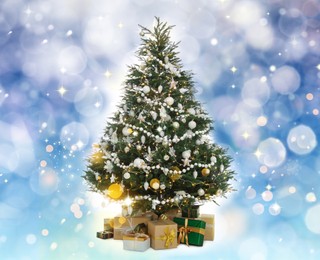 Image of Beautifully decorated Christmas tree and gift boxes on light blue background. Bokeh effect