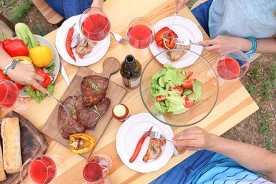 Young people having barbecue at table outdoors, top view