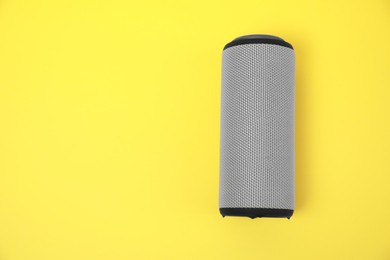 Photo of One portable bluetooth speaker on yellow background, top view with space for text. Audio equipment