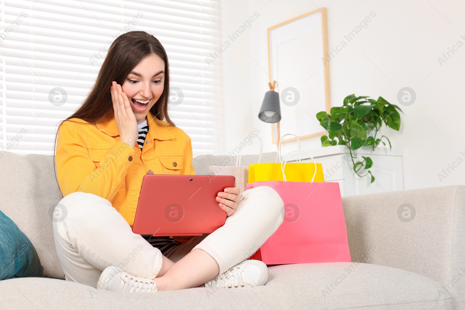 Photo of Special Promotion. Emotional woman looking at laptop on sofa indoors