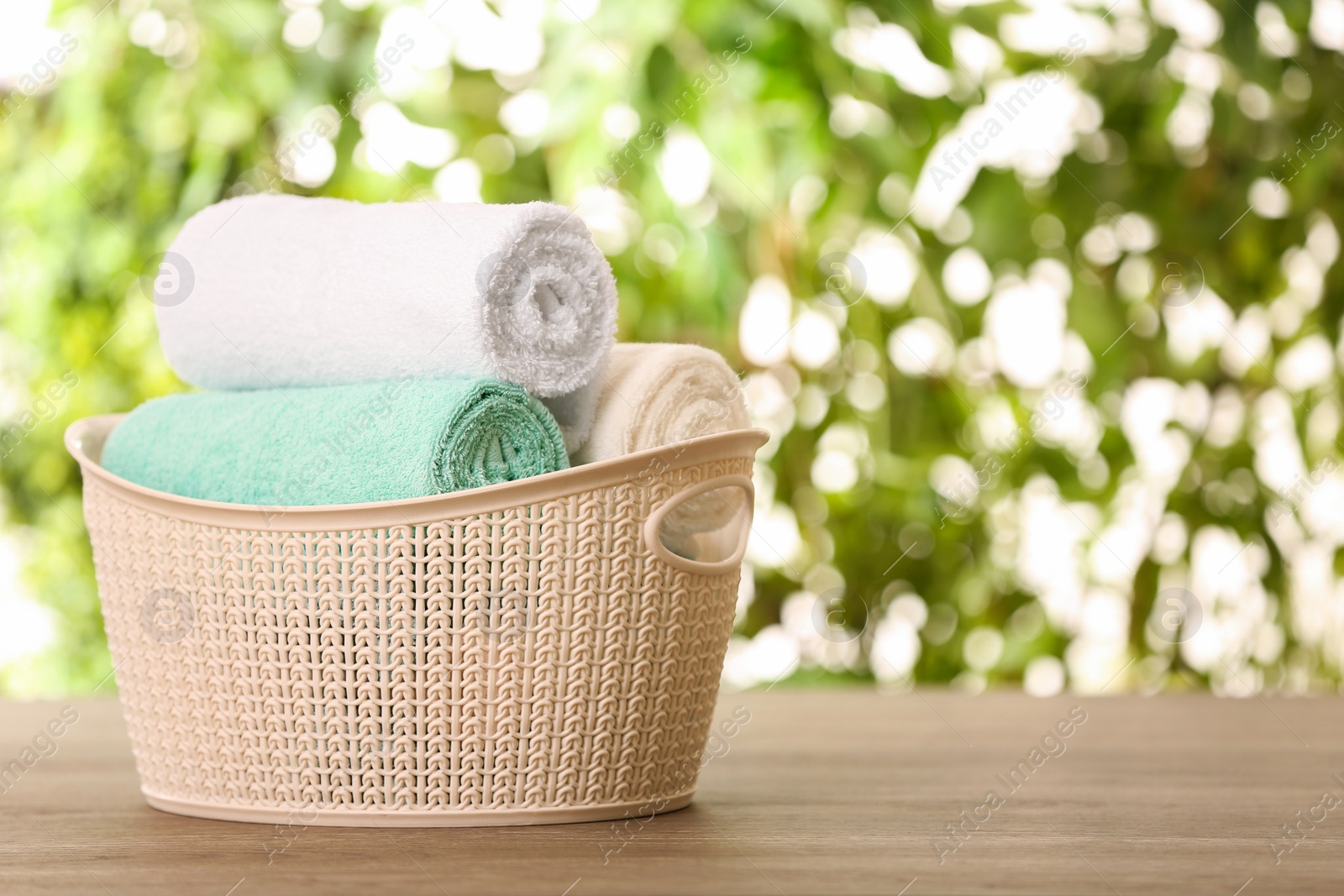 Photo of Basket with clean towels on table against blurred background. Space for text