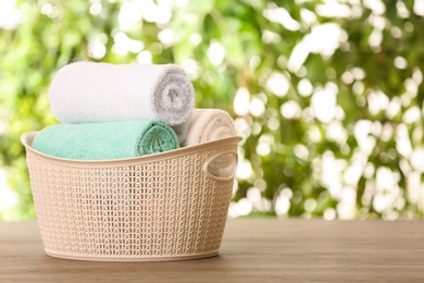 Photo of Basket with clean towels on table against blurred background. Space for text